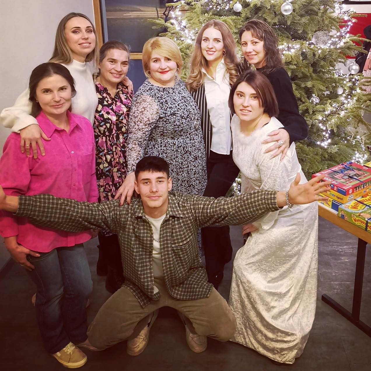 Sieben Frauen und ein junger Mann stehen vor einem geschmückten Weihnachtsbaum.