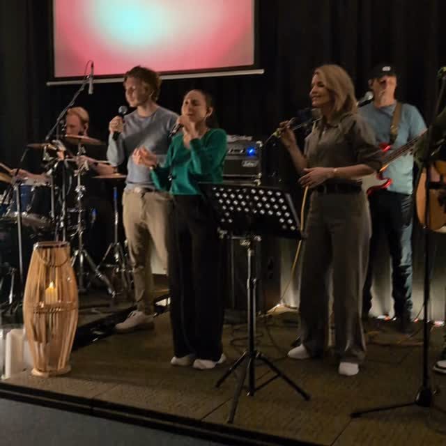 Eine Lobpreisband mit drei Singenden, Schlagzeug und Bass steht auf der Bühne.